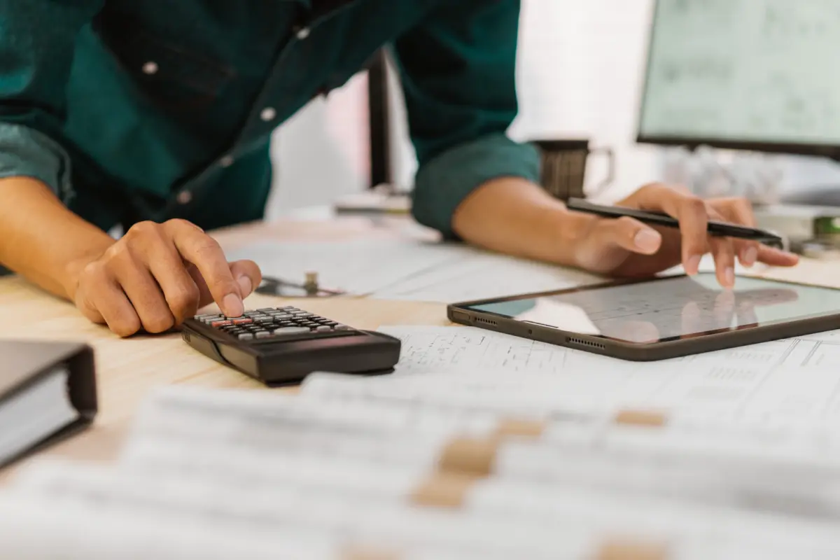 Close up Architect or Engineer pressing on calculator for calculating value estimating for safety with the drawing construction building.